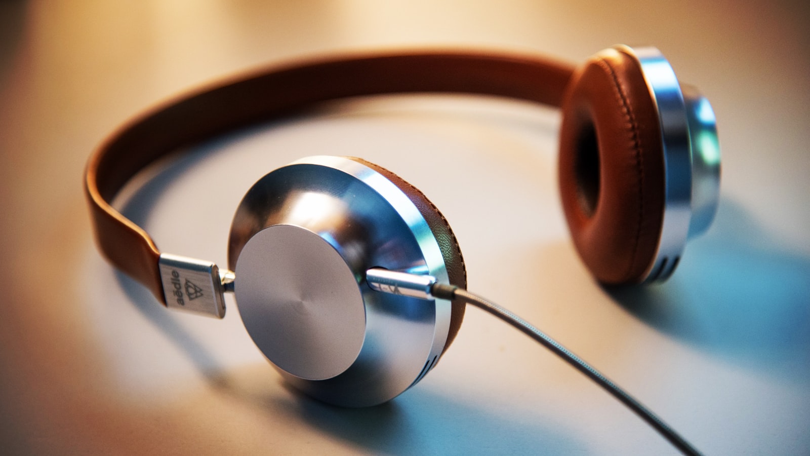 A pair of over-ear headphones resting on a wooden desk beside a notebook