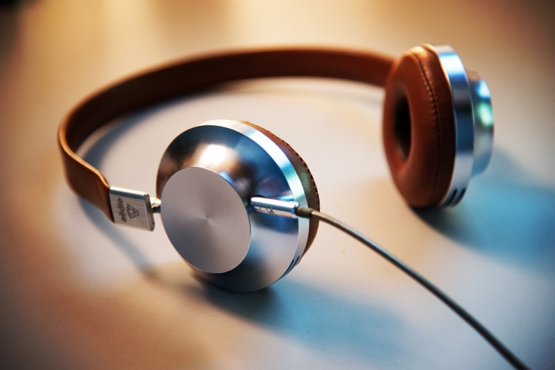 A pair of over-ear headphones resting on a wooden desk beside a notebook